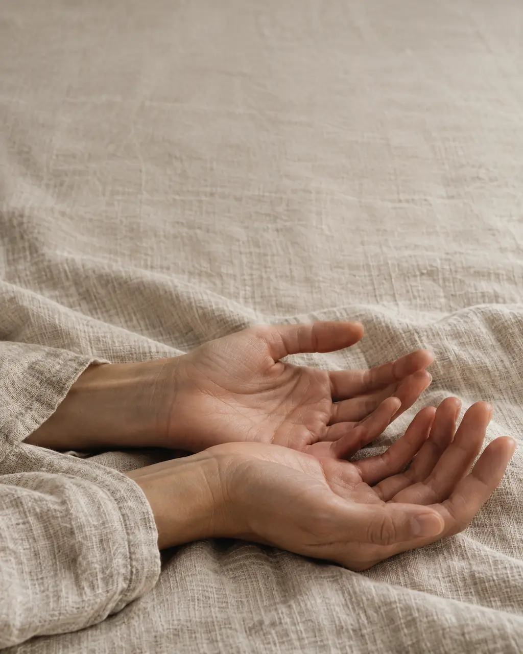Open hands resting on linen